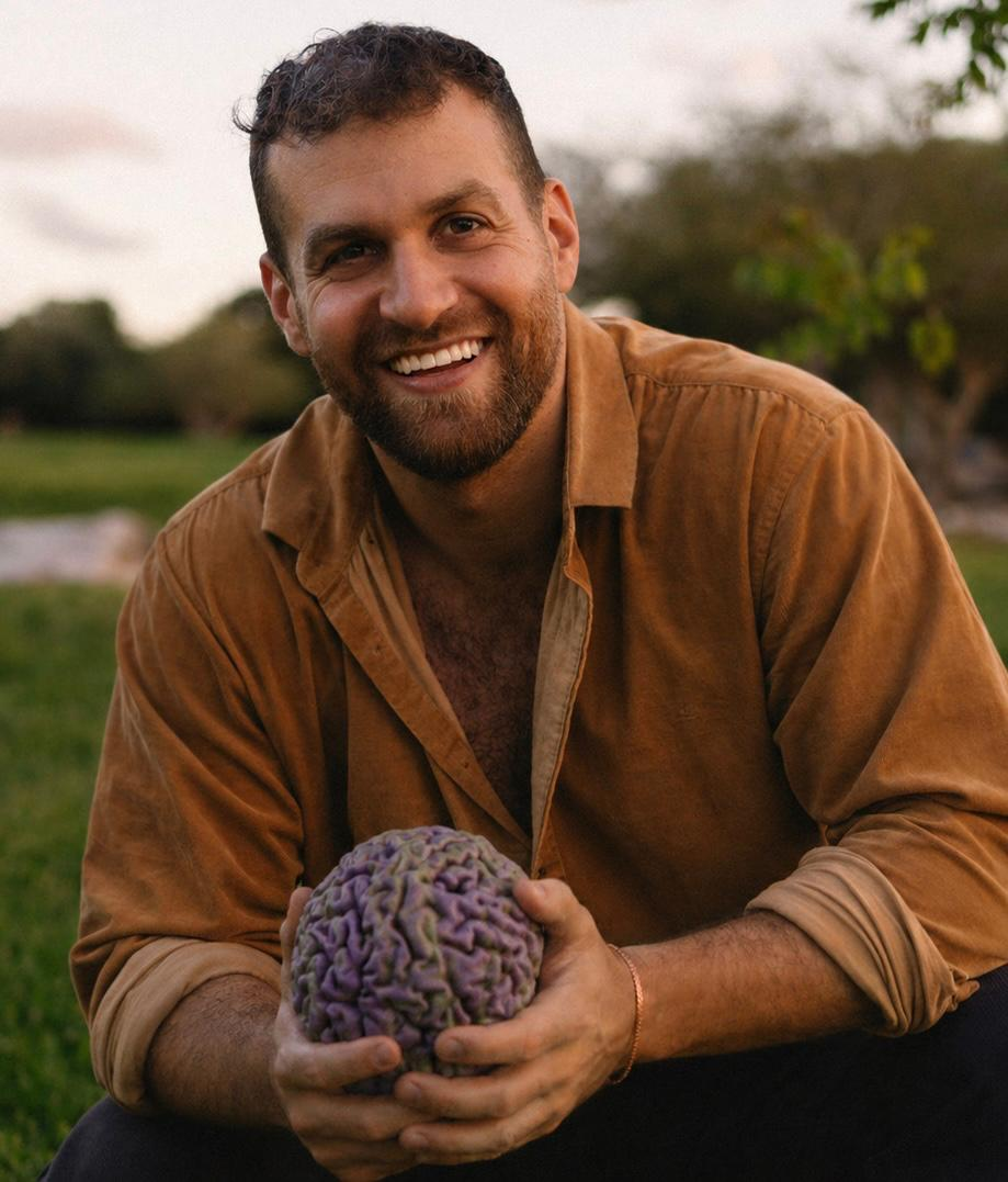 אמיר הררי מחייך ומחזיק דגם של מוחו שהדפיס בתלת מימד
